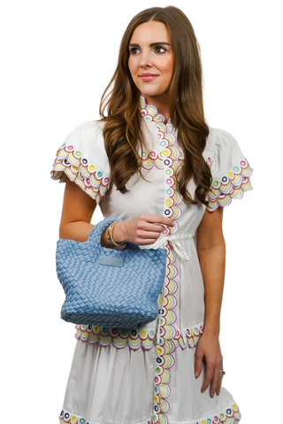 Woman holding a blue textured handbag against a white background