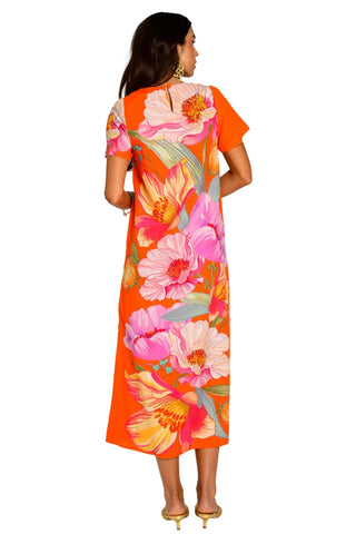 Woman wearing a vibrant floral dress with a white background
