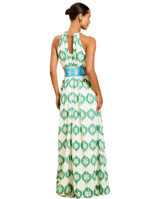 Woman wearing a green and white patterned halter neck dress on a beige background
