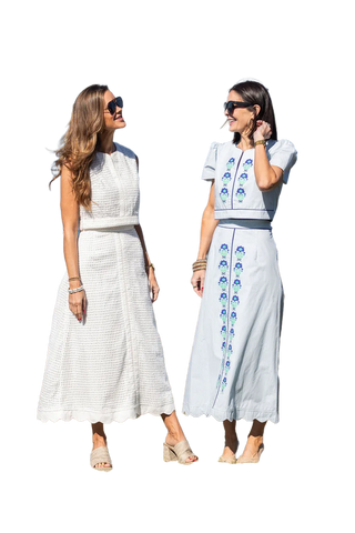 Two women wearing matching outfits with white and blue patterns on a white background