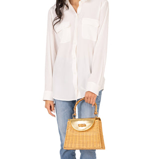 Person wearing a white shirt and blue jeans holding a wicker handbag on a white background