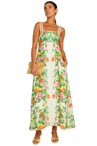 Woman wearing a floral dress holding a clutch against a white background