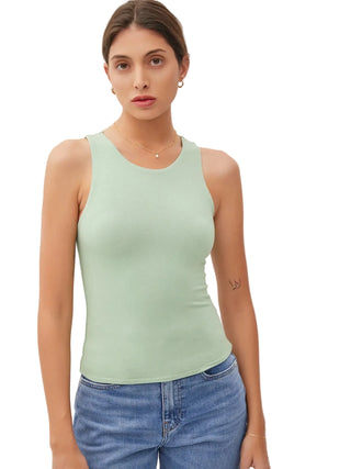 Woman wearing a light green tank top and blue jeans against a white background