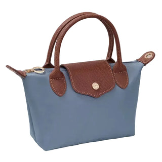 Blue handbag with brown handles and accents on a textured surface.