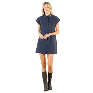 A woman modeling a short-sleeve navy blue shirt dress with a pointed collar and front button placket, paired with dark brown knee-high boots, against a plain white studio background.