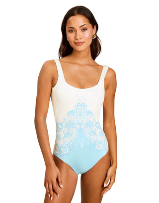 Woman wearing a white and blue one-piece swimsuit on a beige background