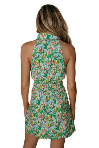 Woman wearing a green floral dress against a plain background