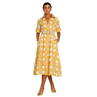 A woman modeling a yellow and white patterned midi shirt dress with a matching belt, standing against a plain white background.