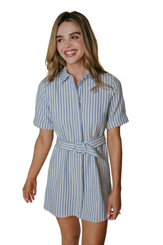 Woman wearing a blue and white striped dress against a beige background