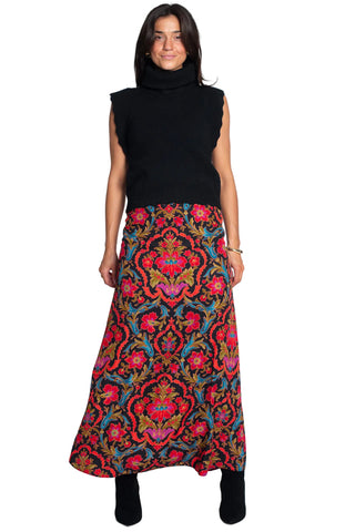 Woman wearing a colorful patterned skirt and black top on a white background