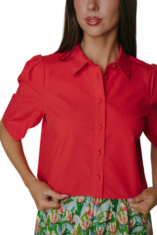 Person wearing a red blouse with short sleeves against a neutral background