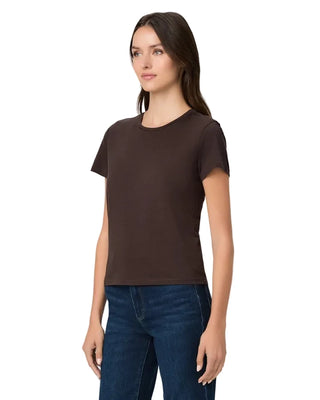A woman modeling a dark brown short-sleeve crewneck t-shirt paired with dark blue jeans, photographed against a solid light gray background.