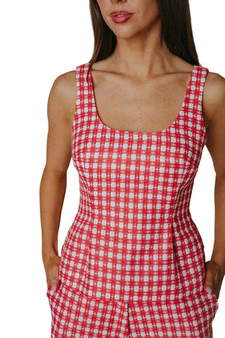 Woman wearing a red and white checkered dress against a neutral background