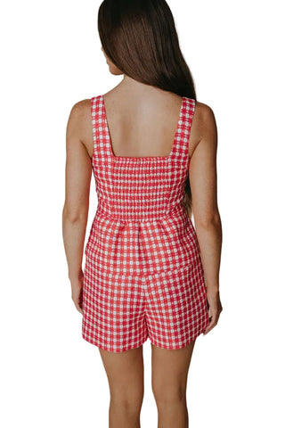Woman wearing a red and white checkered romper against a beige background