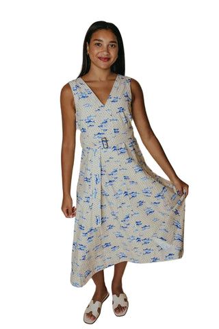 Woman wearing a sleeveless dress with blue and white pattern on a beige background
