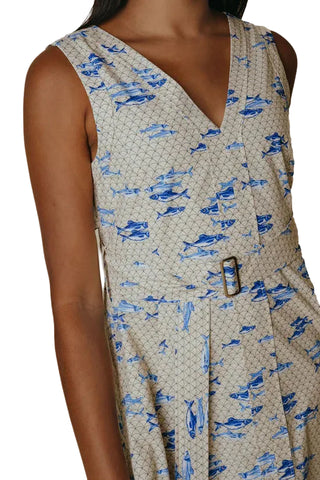 Woman wearing a sleeveless dress with blue fish pattern on a beige background