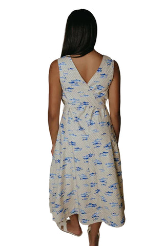 Woman wearing a sleeveless dress with blue pattern on a plain background