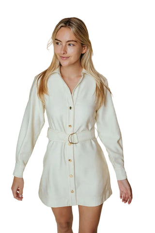 Woman wearing a white shirt dress with a belt on a beige background