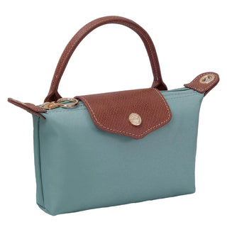 Teal handbag with brown handle and flap on a light background
