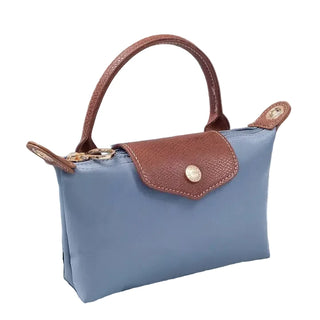 Blue handbag with brown handle and flap on a textured surface