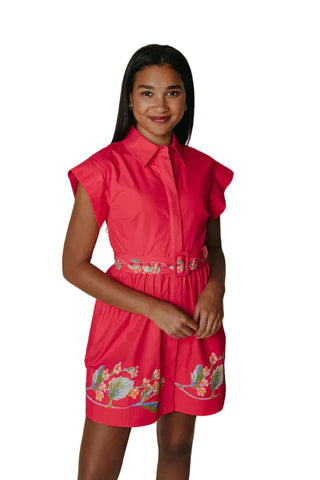Woman wearing a pink dress with floral embroidery on a plain background