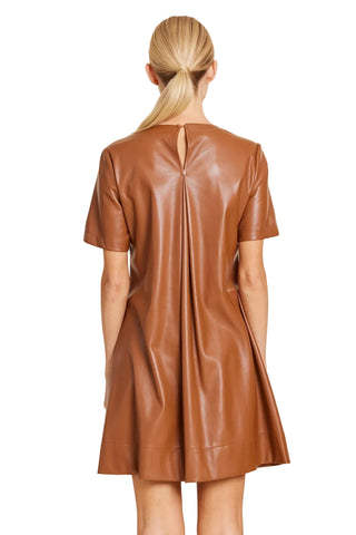 A woman viewed from the back wearing a short-sleeve brown faux-leather dress with a back slit, set against a solid beige background.