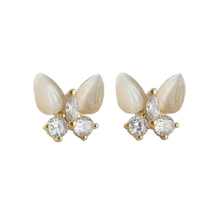 Butterfly-shaped earrings with pearl and crystal details on a light gray background