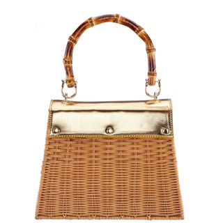 Wicker handbag with a gold top section and bamboo handle on a white background